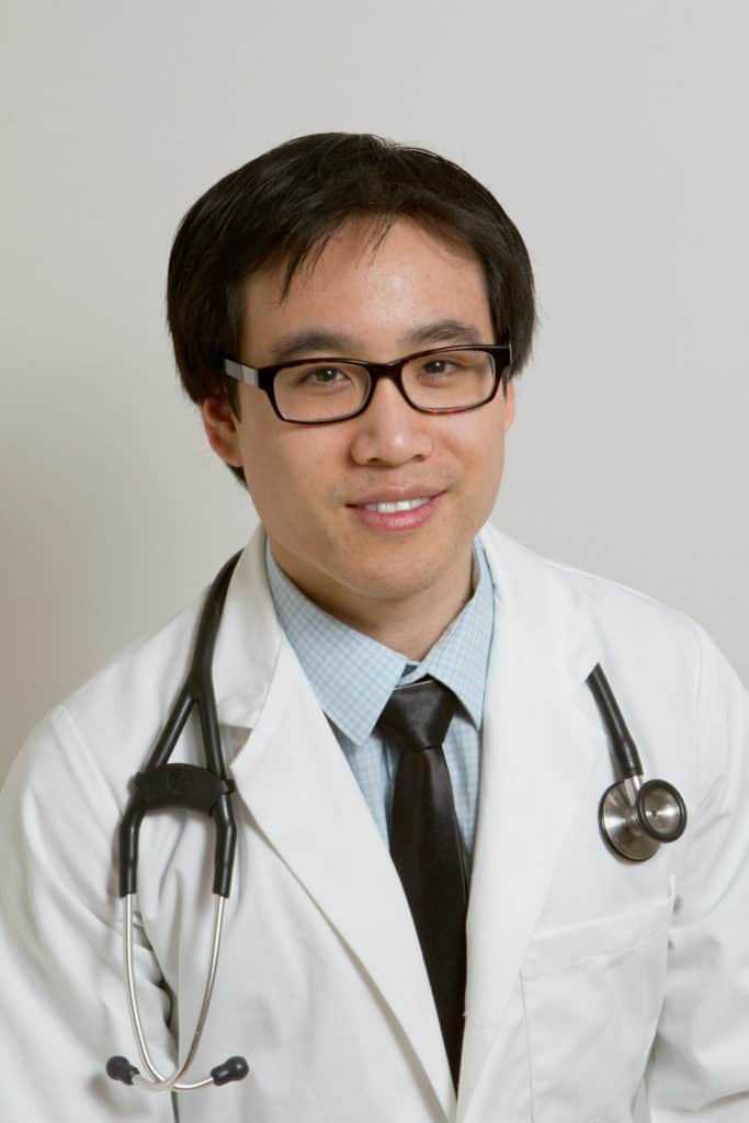 A man in white lab coat and black tie.