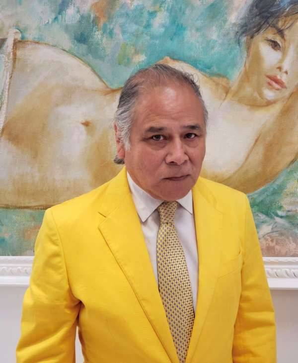 A man in a yellow suit standing next to a painting.