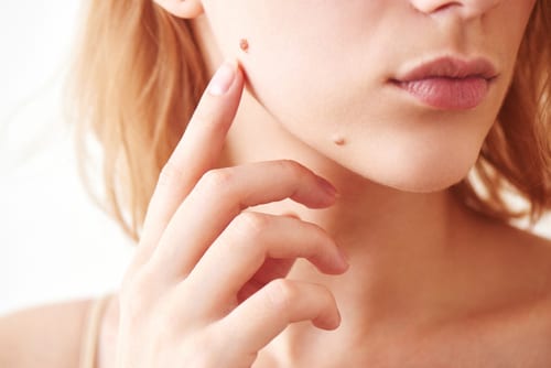 A woman with her hand on her face and one of the two small dots in her ear.