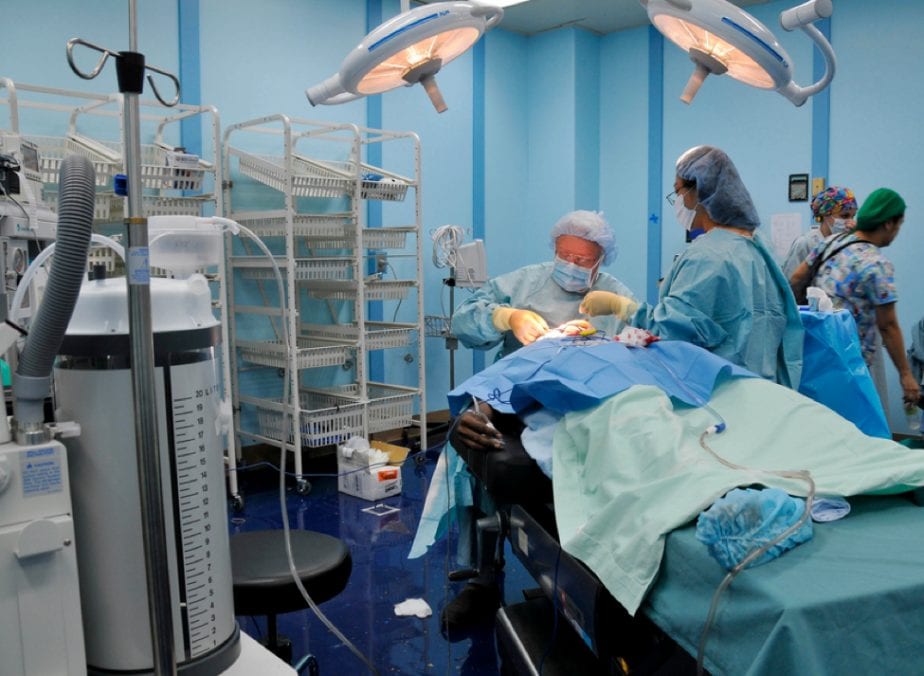 Two surgeons in a room with surgical equipment.