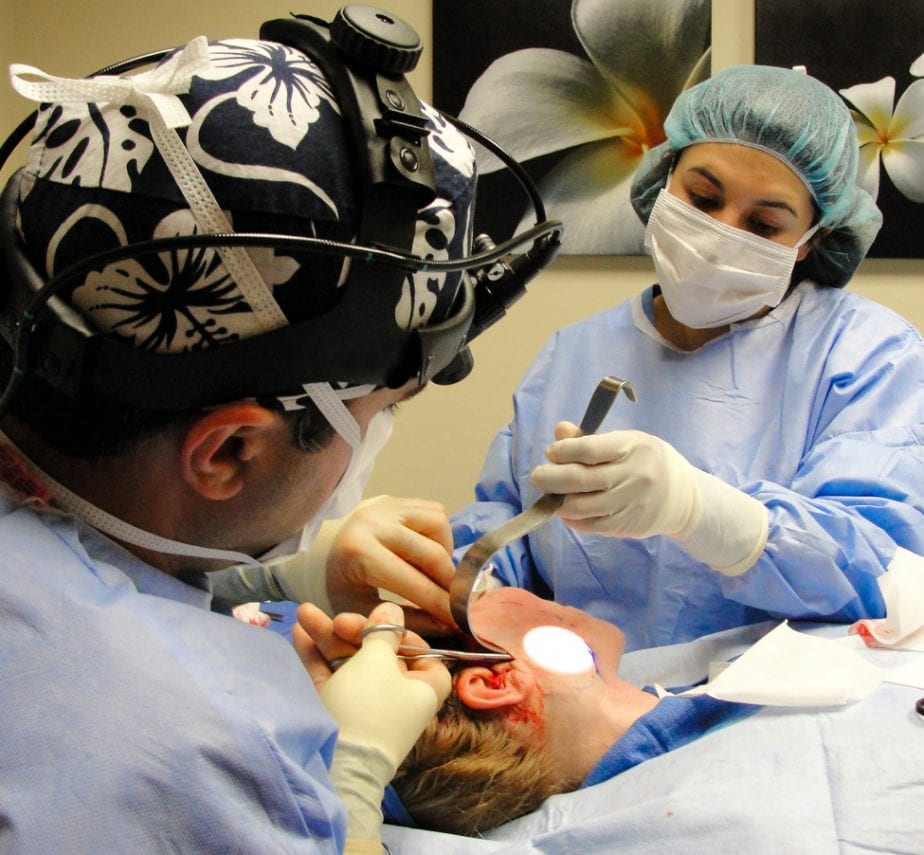 A dentist and his assistant performing an operation on a patient.