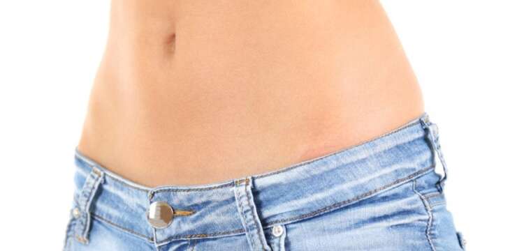 A woman 's stomach in jeans and no shirt.