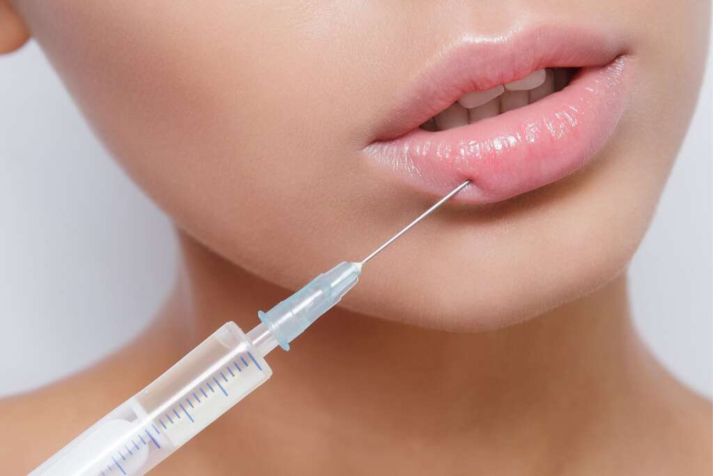 A woman with pink lips is getting an injection.