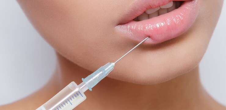 A woman with pink lips is getting an injection.